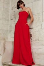 Model wearing Jovani 03529 red jumpsuit, front view with elegant pose, showcasing unique wide-leg overlay.