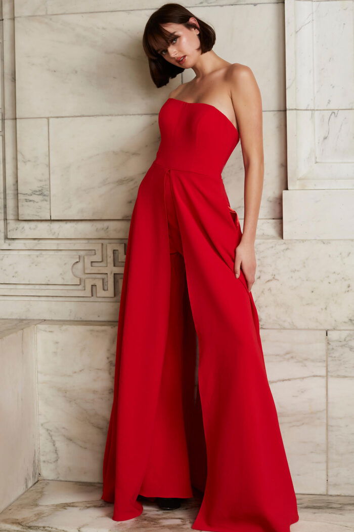 Model wearing Jovani 03529 red jumpsuit, back view, with strapless design and wide-leg flow.