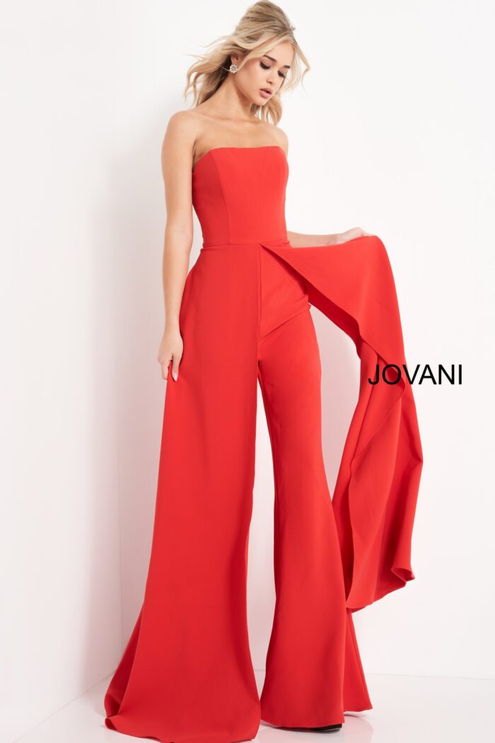 Model wearing Jovani 03529 red jumpsuit, angled view, showcasing the wide-leg cut and elegant overlay.