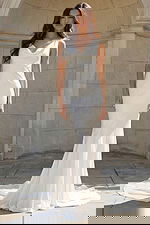 Model wearing a sleek satin gown with a draped cowl neckline and soft train.