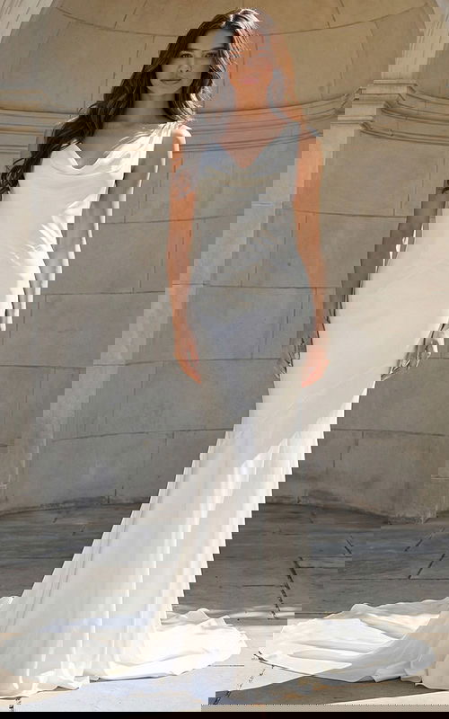 Model wearing a sleek satin gown with a draped cowl neckline and soft train.