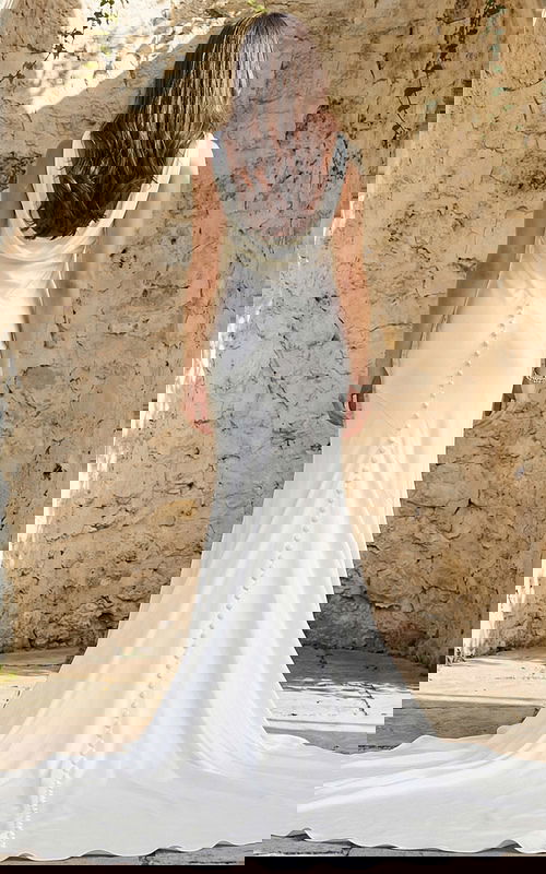 Back view of a fitted satin gown with draped cowl back, button detailing, and flowing train.