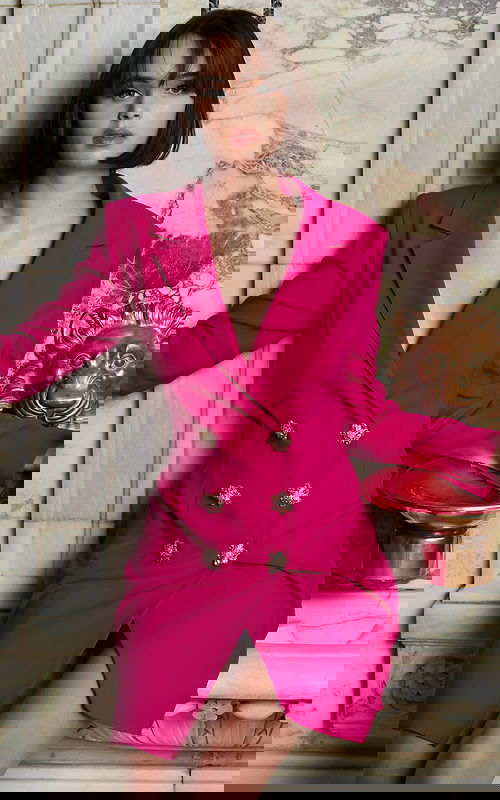 model wearing Jovani 04172 fuchsia blazer dress sitting with floral buttons