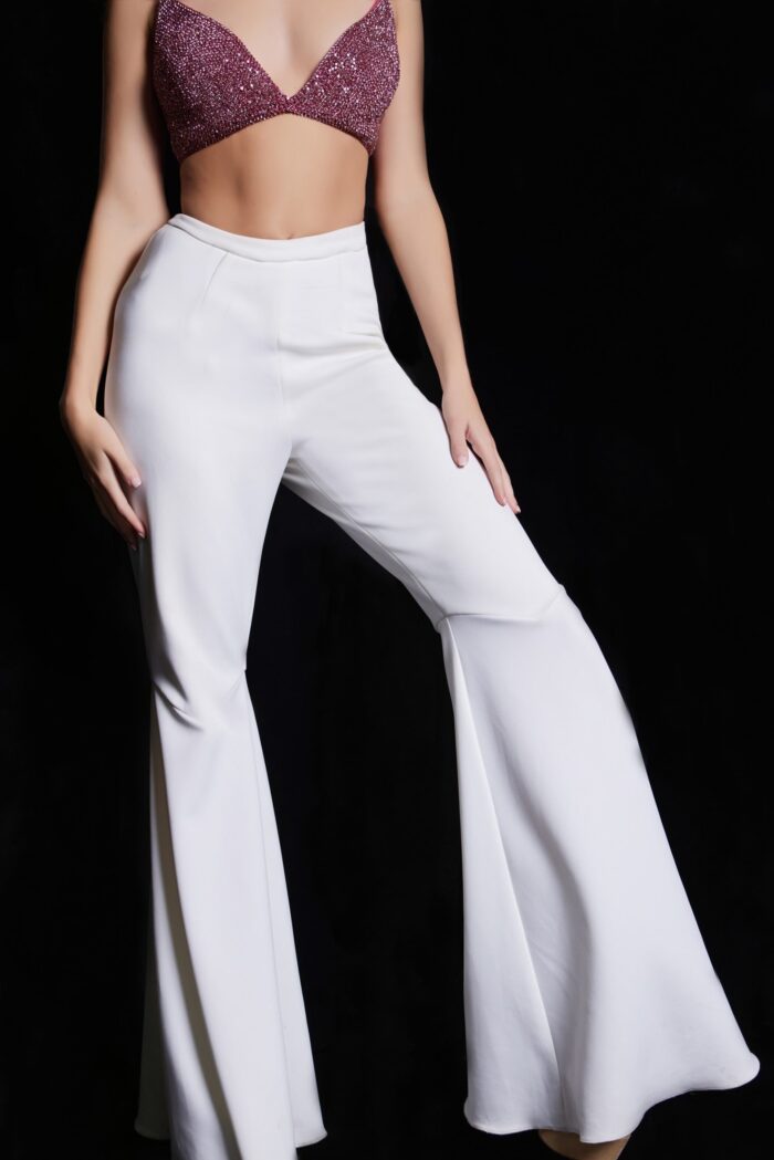 Model wearing Jovani 05308 ensemble with beaded top and white flared pants.