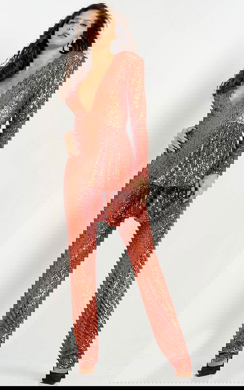 Model wearing Jovani 05345 orange sequin jumpsuit showcasing V-neckline and long sleeves, front view.