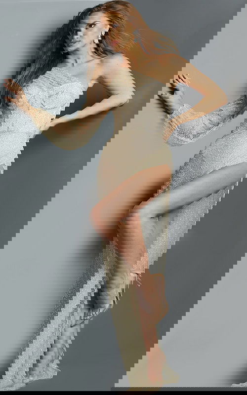 Model wearing Jovani 06082 nude gown with asymmetrical neckline and high slit.