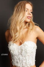 Model in Jovani 06856 off-white crop top shows front details of floral embroidery.