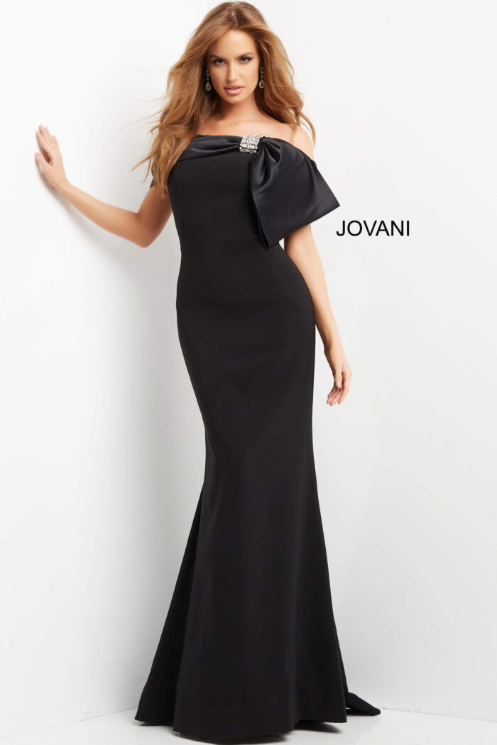 Model wearing Jovani 07014 black off-the-shoulder gown with large bow and embellishment, front view.