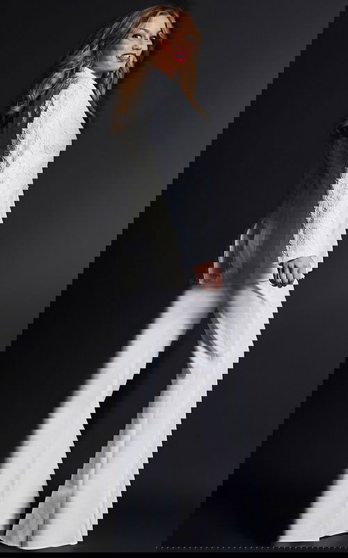 Model wearing Jovani 07551 ivory lace blazer with trousers, back view