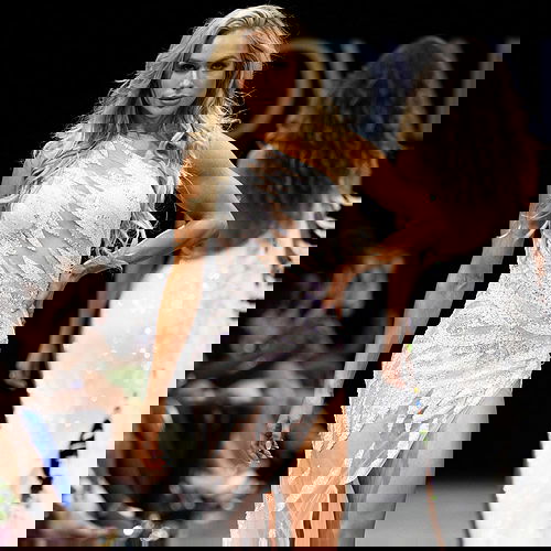 model wearing 07948 white one-shoulder gown with sequin embellishments and high slit