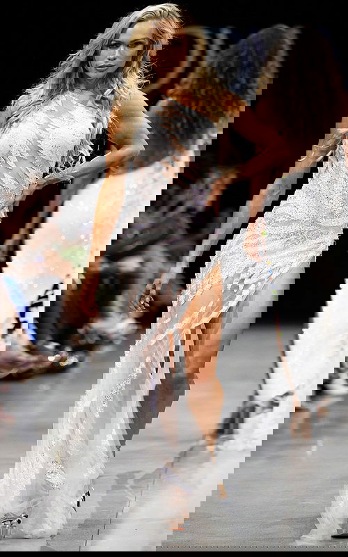 model wearing 07948 white one-shoulder gown with sequin embellishments and high slit