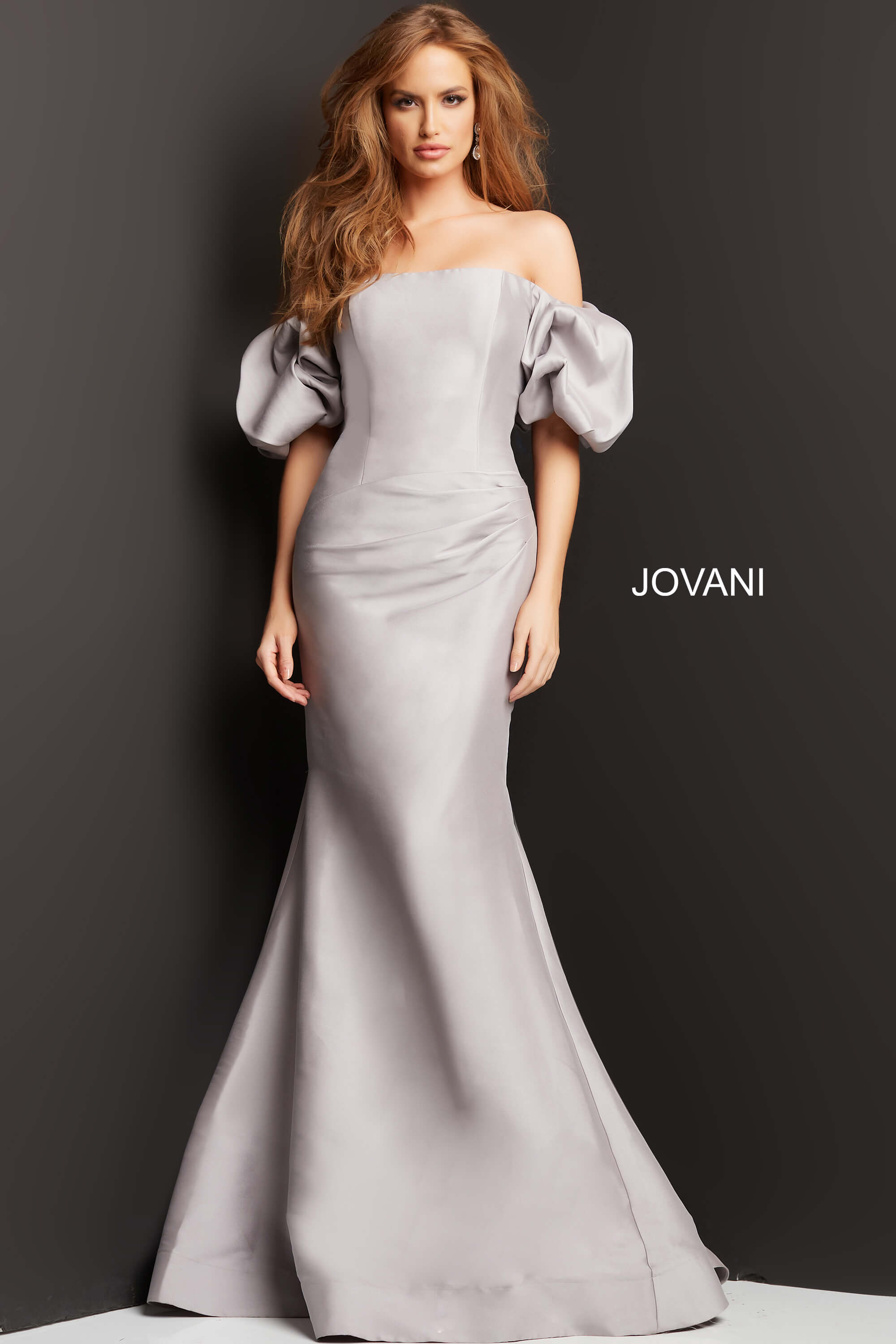 08361-Taupe-201-1.jpg Model wearing Jovani 08361 gown with off-shoulder neckline and puff sleeves, front view.