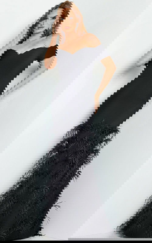 Model wearing Jovani 08384 black off-the-shoulder mermaid gown with feather details.