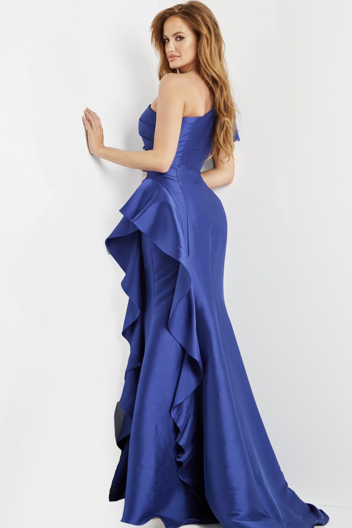 Back view of model wearing Jovani 09201 blue gown with ruffle design and one-shoulder puff sleeve.