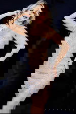 Model wearing Jovani 09483 in nude, displaying intricate beadwork and feather detail.