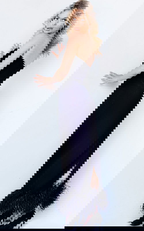 Model wearing Jovani 09630 black evening dress with feather trim, back view.