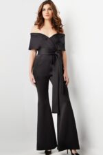 Model wearing Jovani 09726 black off-the-shoulder jumpsuit, another front view