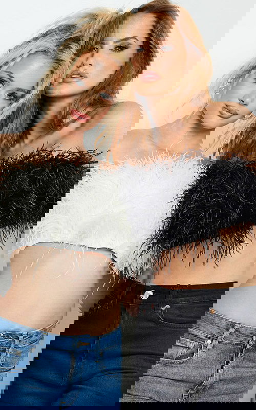 Two models wearing Jovani 09835 tops in black and ivory feathers, off-shoulder design.