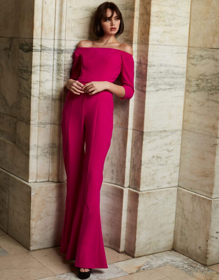 Model wearing Jovani 1867 fuchsia jumpsuit with off-the-shoulder neckline