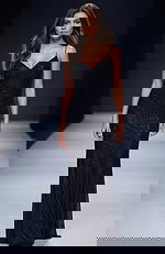 Sleek fitted gown with thin straps, subtle sparkle fabric, and a smooth floor length silhouette creating a clean, elegant look