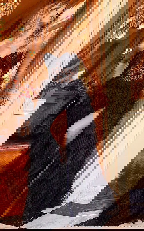 Model wearing Jovani 22226 black gown with tiered ruffles and strapless neckline, front view.