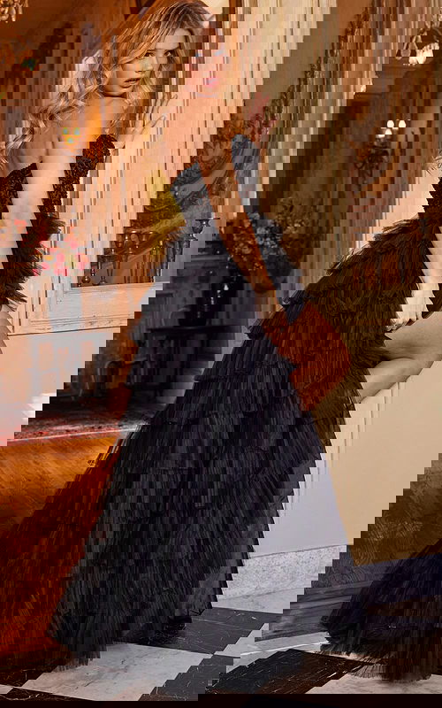 Model wearing Jovani 22226 black gown with cascading ruffles, back view.