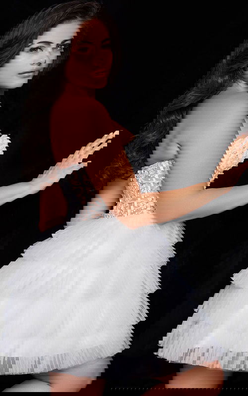 Model in Jovani 22227 offwhite mini dress showing back detail with tiered tulle skirt.