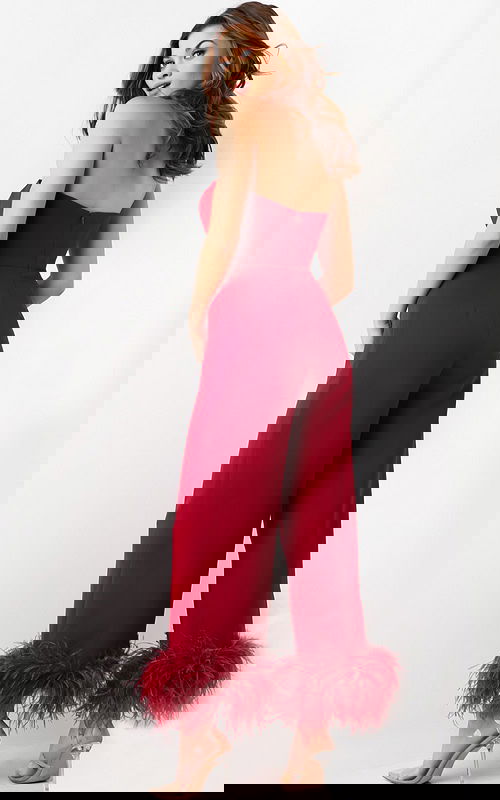 Model wearing Jovani 22590 red strapless jumpsuit with feathered hems, back view.