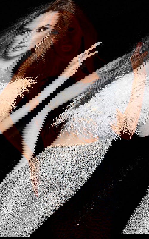 model wearing 22780 featuring a feathered halter top with a sheer rhinestone skirt, front view