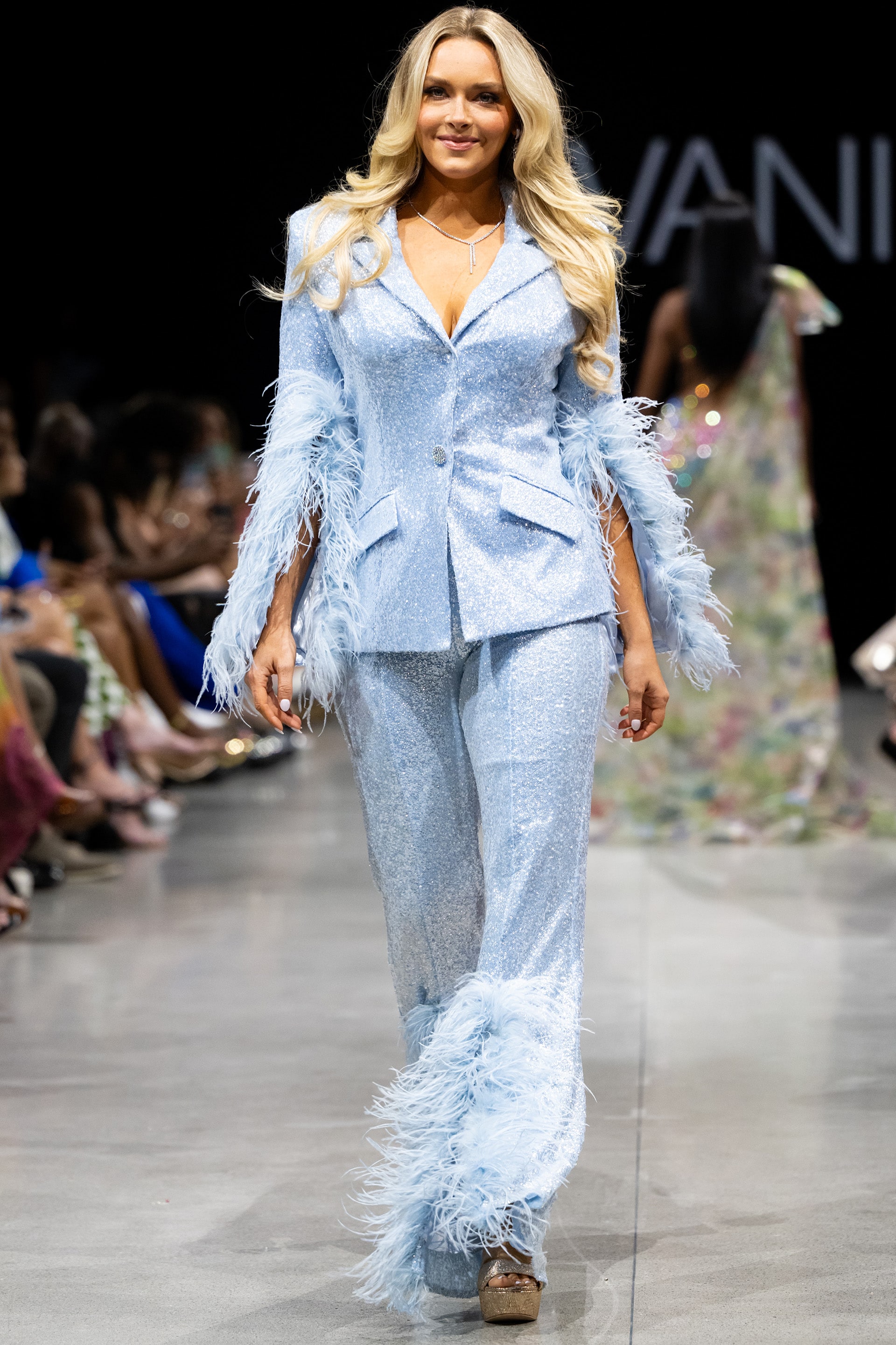 23162.jpg Model wearing Jovani 23162 powder blue pantsuit with feathered sleeves, view from the front.