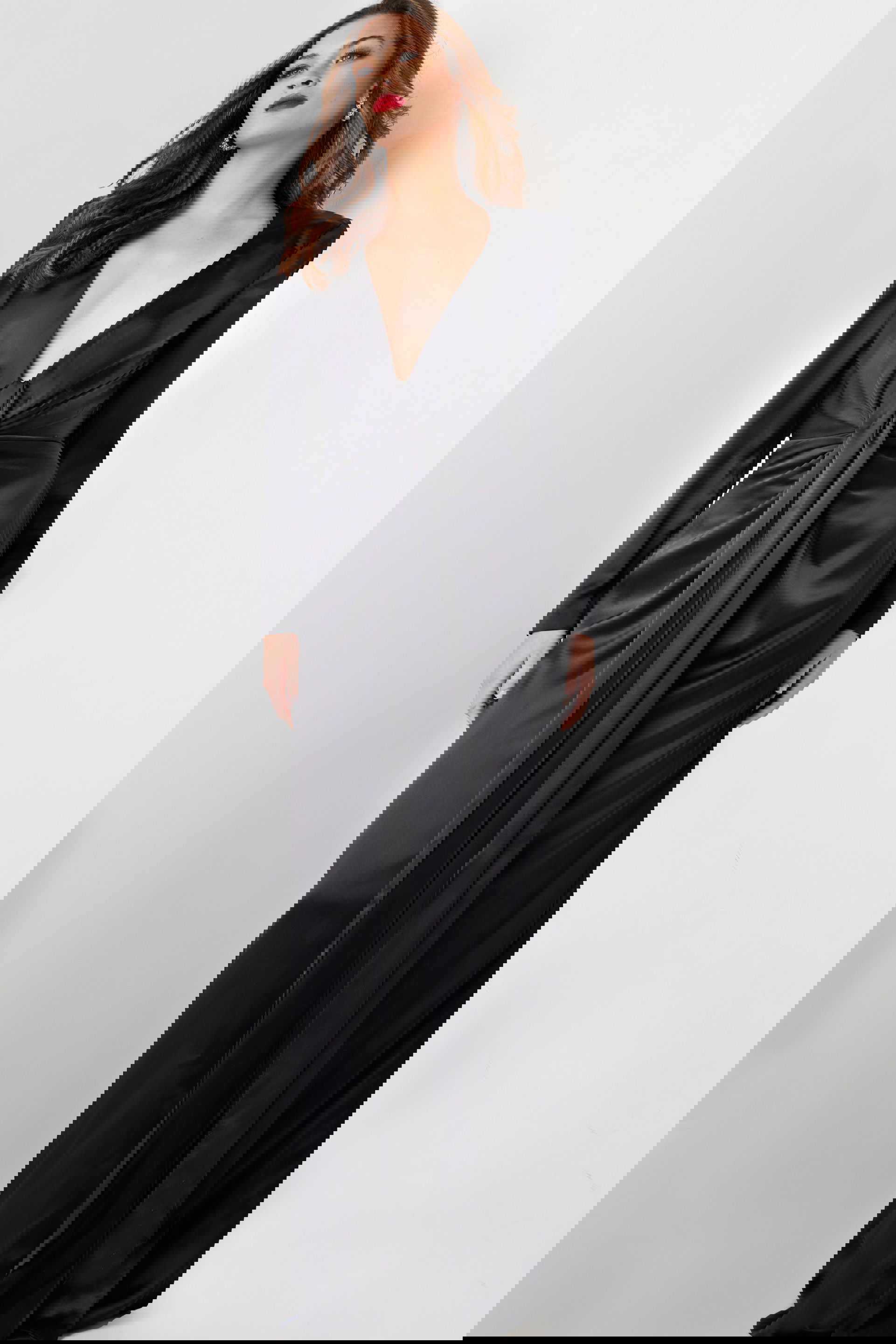 23180-BLACK-7.jpg Model wearing Jovani 23180 elegant black gown with deep V-neckline and knot detail, front view.