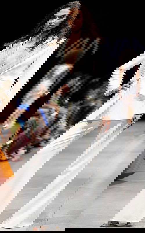 Model wearing Jovani 23336 white suit with embellished lapel and wide-leg pants.