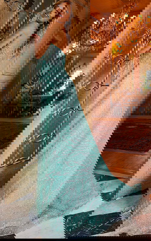 Model wearing Jovani 23361 back view showing train of green gown.