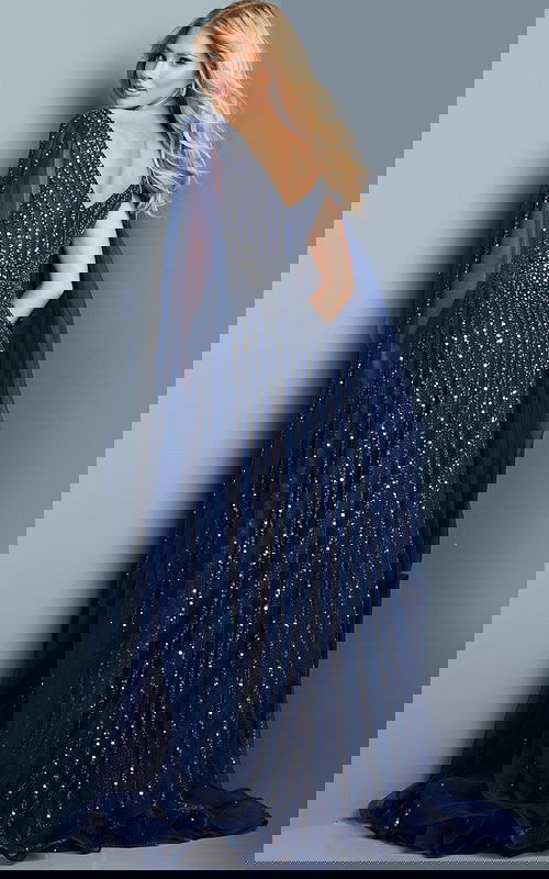 Model wearing Jovani 23362 navy dress with sequins and cape sleeve, back view.