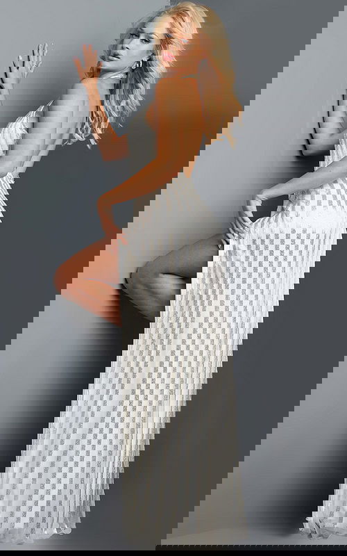 Model showing back of Jovani 23372 white gown with shimmering stripes and open back.