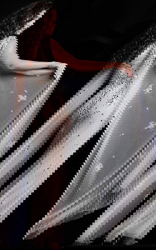 back view of model wearing Jovani 23747 white gown with sheer flowing panels and sequin embellishments