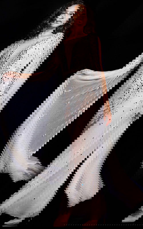 model wearing Jovani 23747 white gown with plunging V-neckline and long sleeves, decorated with sequins and beading