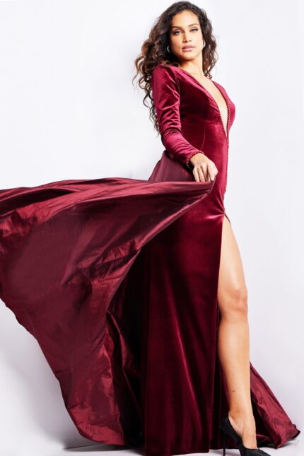Side view of model in Jovani 23943 burgundy gown, highlighting the elegant flow and high slit.