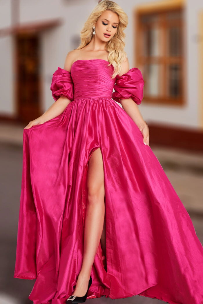 Model wearing Jovani 24099 fuchsia gown with high slit, off-the-shoulder neckline and puff sleeves.