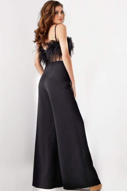 Model wearing Jovani 24144 black jumpsuit with feathered bodice, back view.