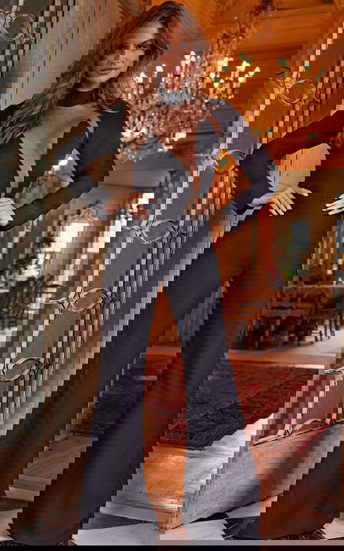 Model wearing Jovani 24297 front view showcasing black jumpsuit with sheer neckline and long sleeves.