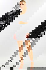 Model wearing a shiny black embossed crop top and matching mini skirt set with a cropped jacket, front view.