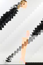 Side angle of model in black embossed skirt suit showing textured details.