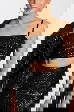 Close-up of crop top and skirt with detailed embossed floral design in black patent fabric.