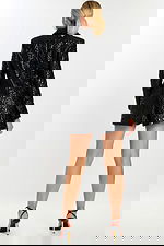 Back view of model in fitted black floral embossed blazer-style romper.