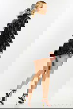 Side view of model showing structured tailoring and glossy floral texture of black romper.