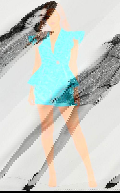 Model wearing Jovani 24623 blue romper with a V-neckline and ruffled cap sleeves.