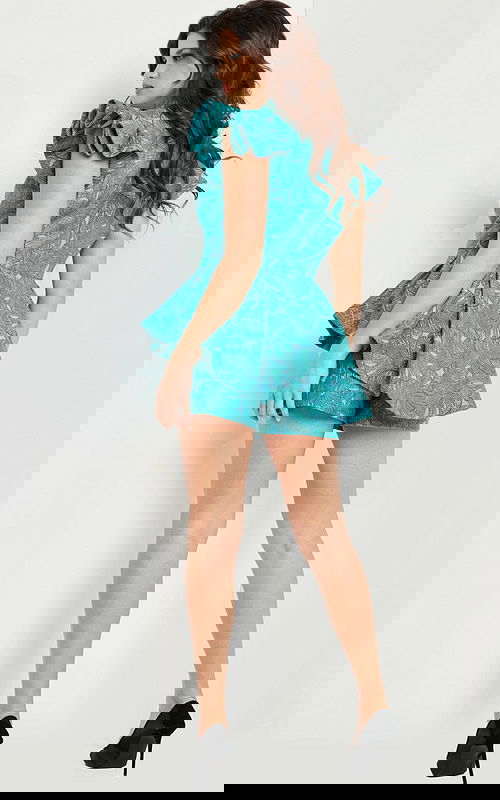 Side angle of model in Jovani 24623 blue romper with detailed fabric texture.