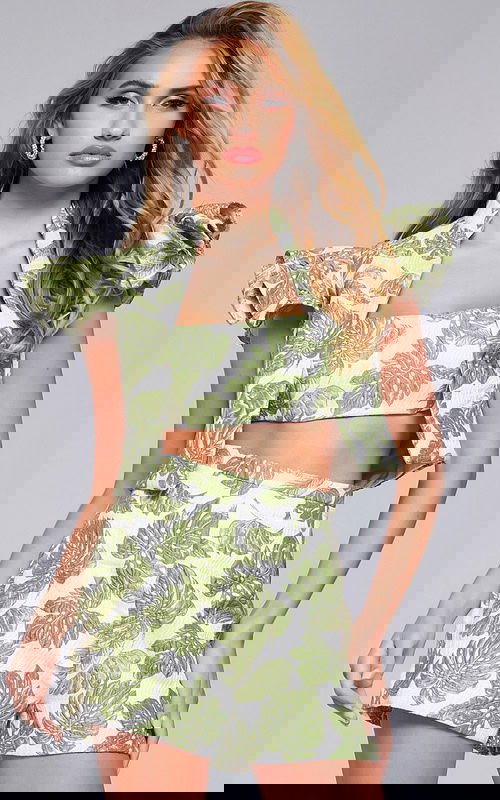 Model wearing Jovani 24649 two-piece set, front view with leaf print and ruffled sleeves.