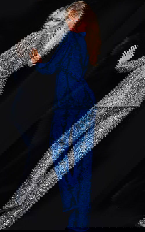 Back view of model wearing Jovani 25886 blue sequin ensemble showcasing jacket details